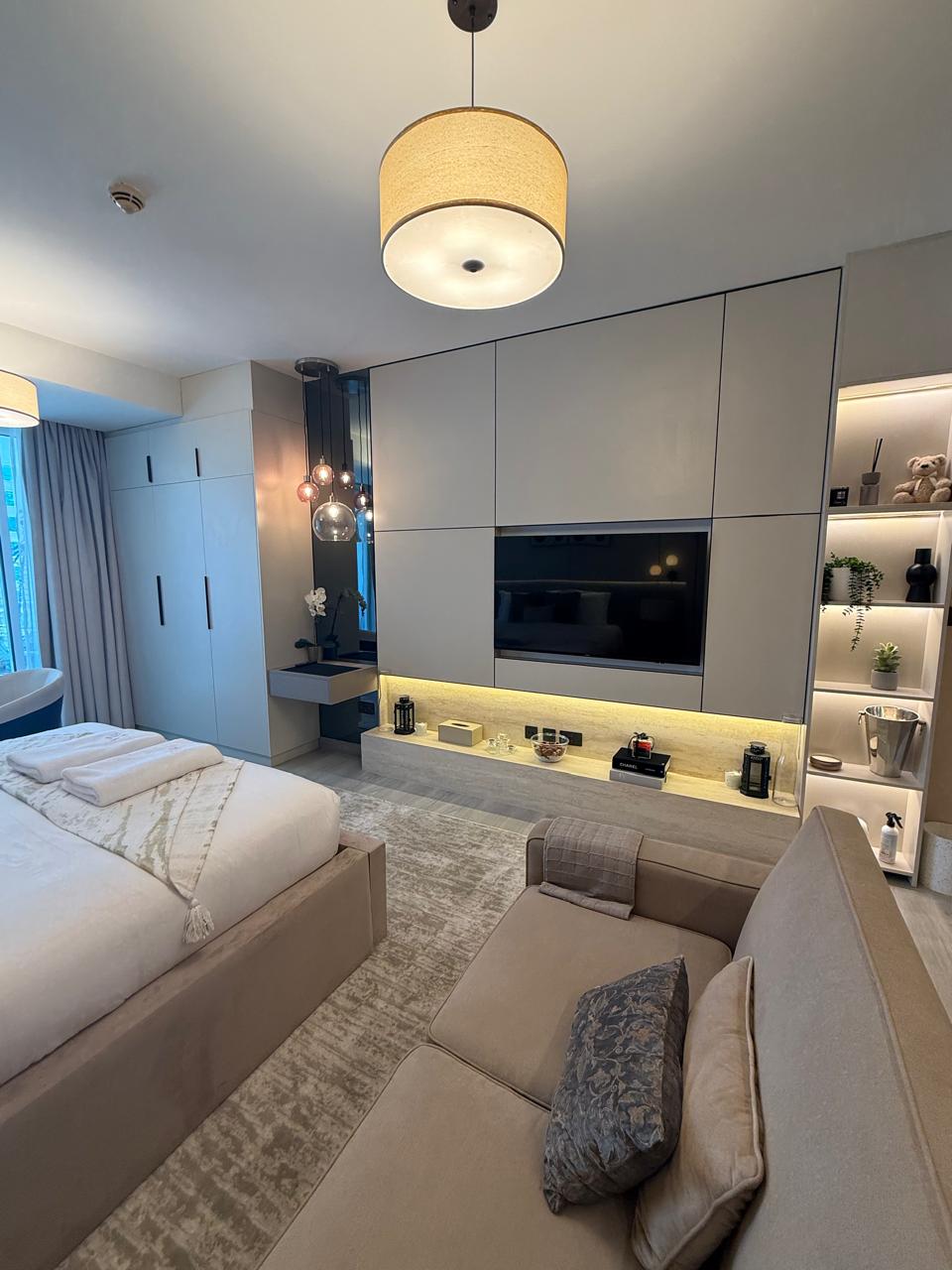 Bedroom with panelled media wall and warm cove lighting