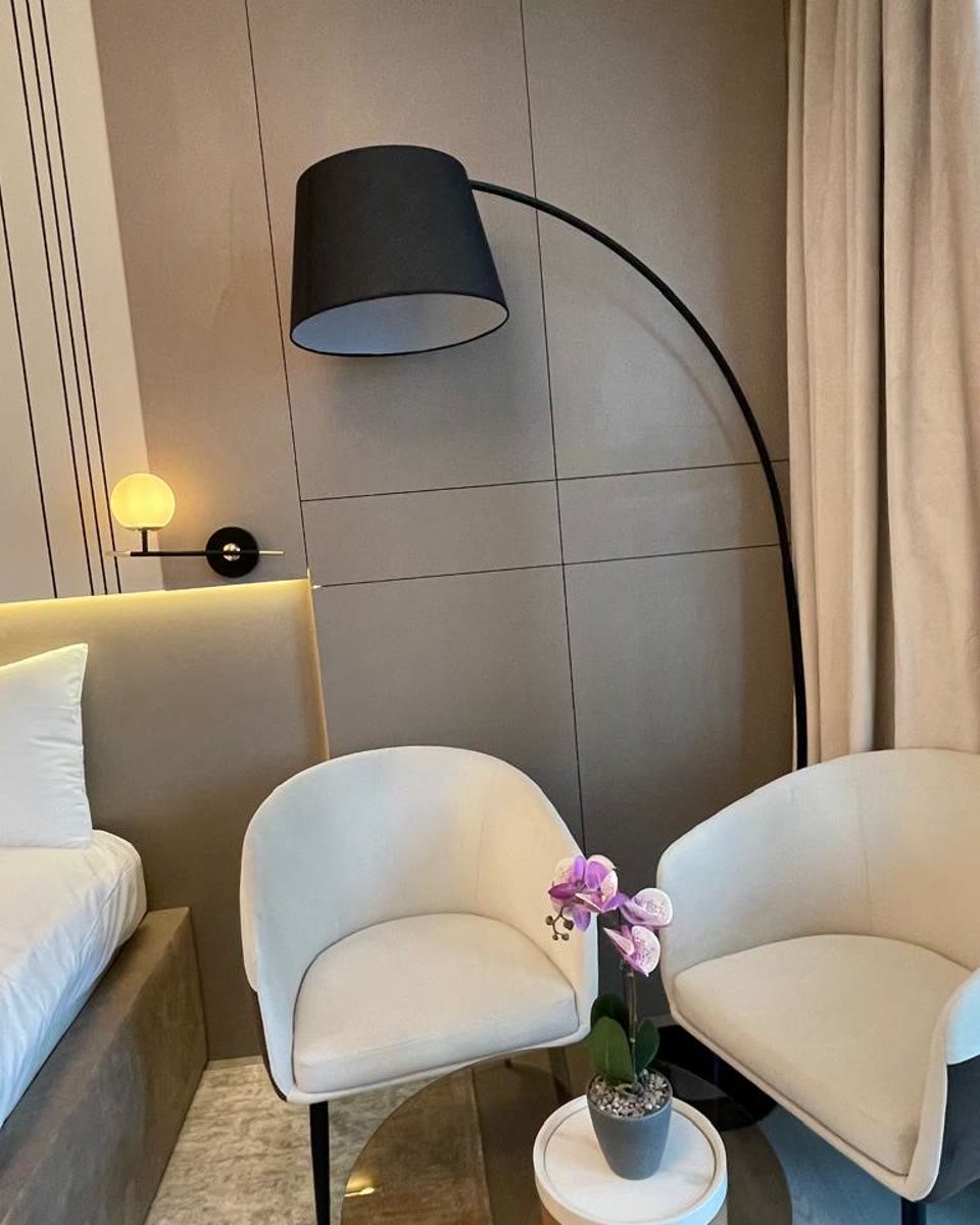 The finished studio: cream armchairs, orchid, warm lighting